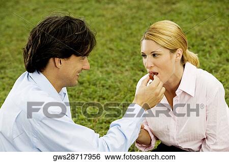 Side profile of a businessman feeding a cherry to a businesswoman View Large Photo Image Stock Photograph - Side profile of a businessman feeding a cherry to a businesswoman. Fotosearch