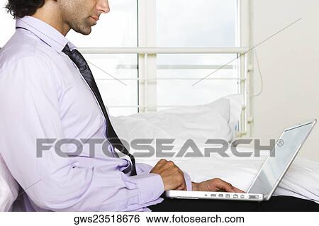 Side profile of a businessman using a laptop View Large Photo Image Stock Photograph - Side profile of a businessman using a laptop. Fotosearch