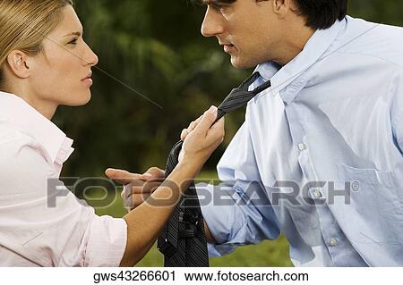 Stock Image - Side profile of a businesswoman holding a businessman's tie. Fotosearch