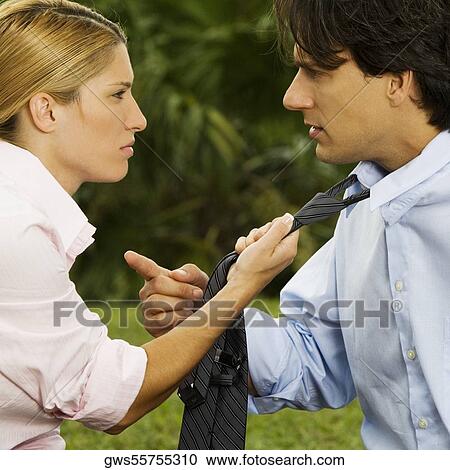 Stock Image - Side profile of a businesswoman holding a businessman's tie. Fotosearch