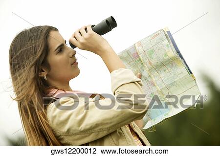 Stock Image - Side profile of a girl looking through a pair of binoculars. Fotosearch