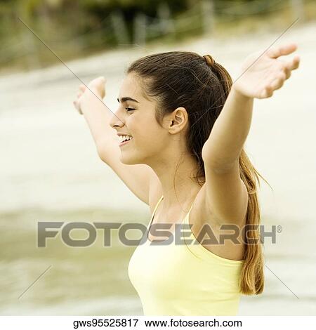 Side profile of a girl standing on the beach with her arms outstretched View Large Photo Image Stock Photo - Side profile of a girl standing on the beach with her arms outstretched. Fotosearch