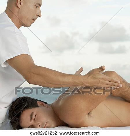 Side profile of a mature man giving a mid adult man a back massage View Large Photo Image Stock Image - Side profile of a mature man giving a mid adult man a back massage. Fotosearch
