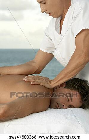 Side profile of a mature man giving a mid adult man a back massage View Large Photo Image Stock Photo - Side profile of a mature man giving a mid adult man a back massage. Fotosearch