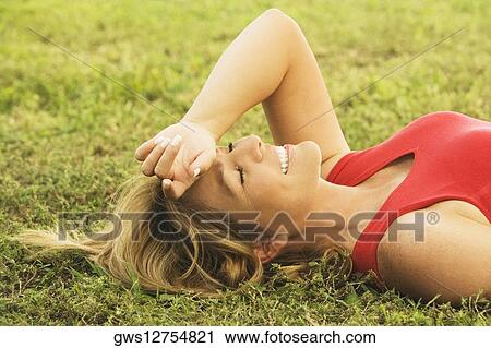Stock Image - Side profile of a mature woman lying on the lawn. Fotosearch