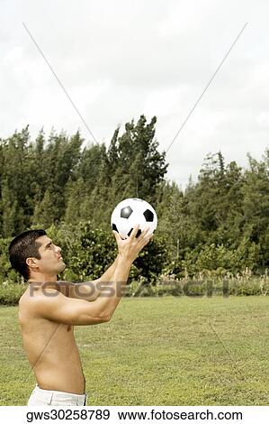 Side profile of a mid adult man holding a soccer ball View Large Photo Image Stock Photo - Side profile of a mid adult man holding a soccer ball. Fotosearch