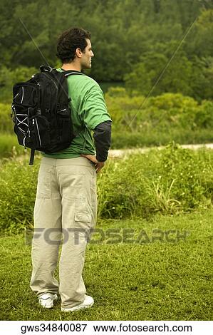 Stock Photo - Side profile of a mid adult man standing with a backpack. Fotosearch