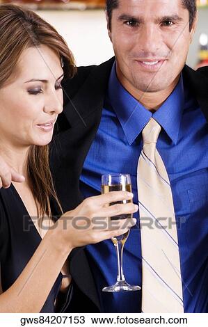 Stock Image - Side profile of a mid adult woman holding a glass of champagne with a mid adult man beside her. Fotosearch