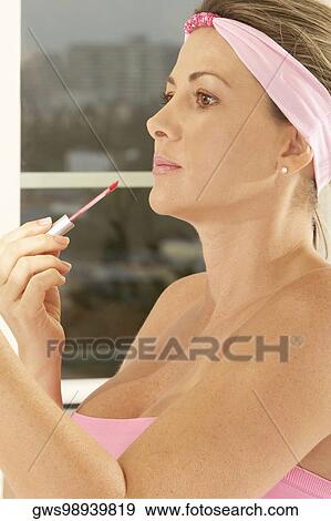 Side profile of a mid adult woman applying lip gloss View Large Photo Image Stock Photo - Side profile of a mid adult woman applying lip gloss. Fotosearch