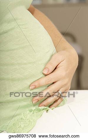 Side profile of a pregnant woman touching her abdomen View Large Photo Image Stock Photo - Side profile of a pregnant woman touching her abdomen. Fotosearch