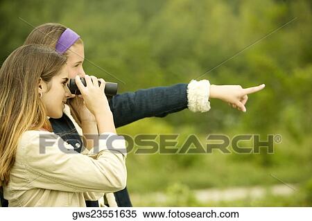 Side profile of a teenage girl pointing forward with a girl looking through a pair of binoculars View Large Photo Image Stock Photography - Side profile of a teenage girl pointing forward with a girl looking through a pair of binoculars. Fotosearch