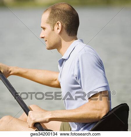 Side profile of a young man kayaking in a lake View Large Photo Image Picture - Side profile of a young man kayaking in a lake. Fotosearch