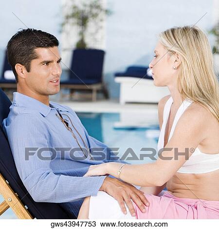 Side profile of a young woman and a mid adult man sitting on a deck chair View Large Photo Image Stock Image - Side profile of a young woman and a mid adult man sitting on a deck chair. Fotosearch