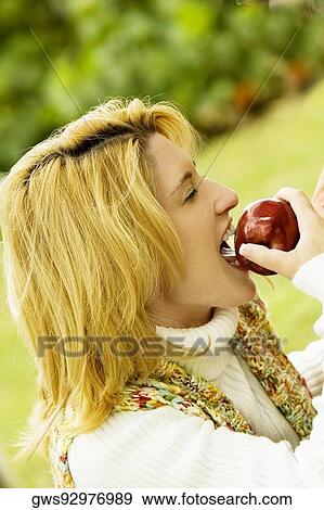 Side profile of a young woman eating an apple View Large Photo Image Stock Photo - Side profile of a young woman eating an apple. Fotosearch