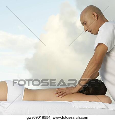 Side profile of a young woman getting a back massage View Large Photo Image Picture - Side profile of a young woman getting a back massage. Fotosearch