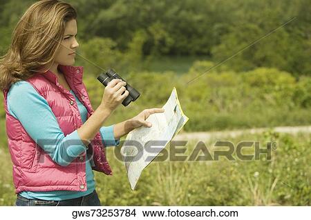 Side profile of a young woman holding a map and a pair of binoculars View Large Photo Image Picture - Side profile of a young woman holding a map and a pair of binoculars. Fotosearch