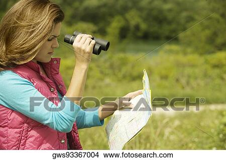 Picture - Side profile of a young woman holding a map and a pair of binoculars. Fotosearch