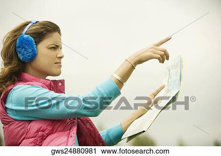 Side profile of a young woman holding a map and pointing forward View Large Photo Image Stock Image - Side profile of a young woman holding a map and pointing forward. Fotosearch