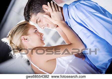 Stock Image - Side profile of a young woman holding a mid adult man's face. Fotosearch
