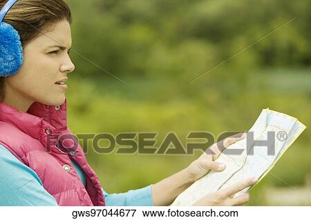 Side profile of a young woman holding a map View Large Photo Image Stock Photo - Side profile of a young woman holding a map. Fotosearch