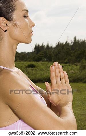 Side profile of a young woman in a prayer position View Large Photo Image Stock Image - Side profile of a young woman in a prayer position. Fotosearch