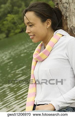 Side profile of a young woman leaning against a tree trunk View Large Photo Image Stock Image - Side profile of a young woman leaning against a tree trunk. Fotosearch