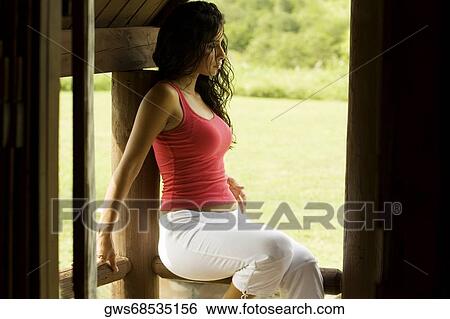 Side profile of a young woman leaning against a wooden column View Large Photo Image Stock Photograph - Side profile of a young woman leaning against a wooden column. Fotosearch