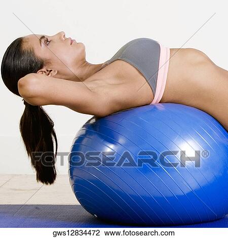 Side profile of a young woman lying over a fitness ball View Large Photo Image Stock Image - Side profile of a young woman lying over a fitness ball. Fotosearch
