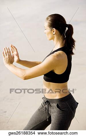 Side profile of a young woman practicing martial arts on the beach View Large Photo Image Picture - Side profile of a young woman practicing martial arts on the beach. Fotosearch