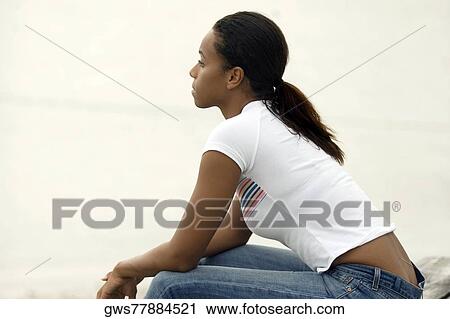 Stock Image - Side profile of a young woman sitting. Fotosearch