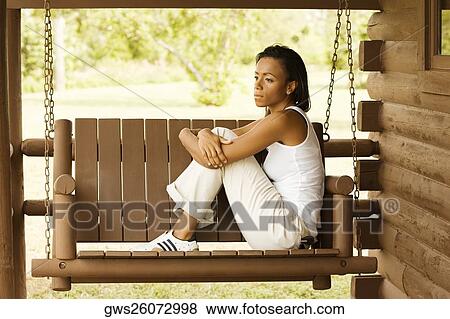Side profile of a young woman sitting on a porch swing View Large Photo Image Stock Photo - Side profile of a young woman sitting on a porch swing. Fotosearch