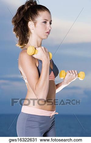 Side profile of a young woman exercising with dumbbells View Large Photo Image Stock Image - Side profile of a young woman exercising with dumbbells. Fotosearch