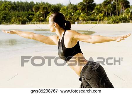 Stock Photo - Side profile of a young woman practicing martial arts on the beach. Fotosearch