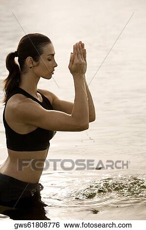 Stock Photograph - Side profile of a young woman meditating in a lake. Fotosearch