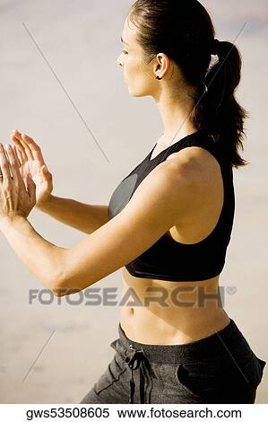 Stock Photography - Side profile of a young woman practicing martial arts on the beach. Fotosearch