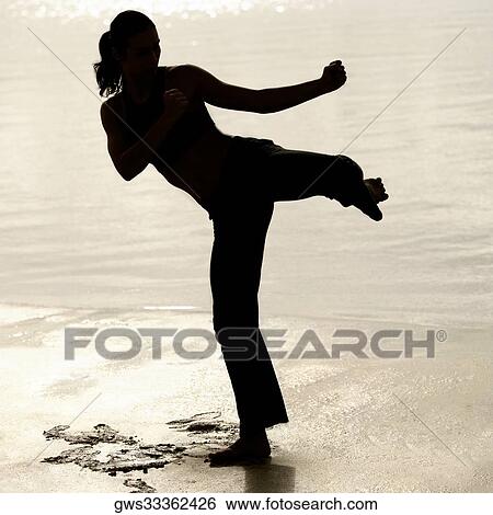 Silhouette of a young woman practicing martial arts on the beach View Large Photo Image Stock Photograph - Silhouette of a young woman practicing martial arts on the beach. Fotosearch