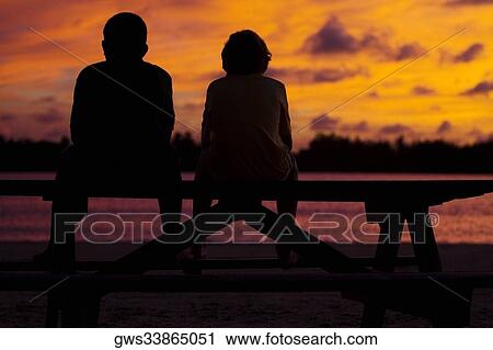 Stock Image - Silhouette of two boys sitting on a picnic table. Fotosearch