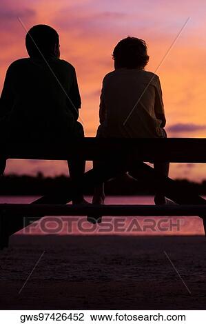 Silhouette of two boys sitting on a picnic table View Large Photo Image Stock Image - Silhouette of two boys sitting on a picnic table. Fotosearch