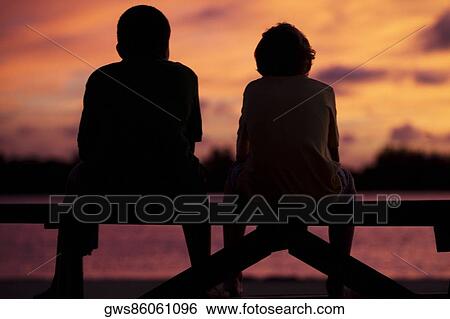 Silhouette of two boys sitting on a picnic table View Large Photo Image Stock Photograph - Silhouette of two boys sitting on a picnic table. Fotosearch