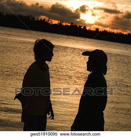 Stock Photography - Silhouette of two boys standing on the beach. Fotosearch