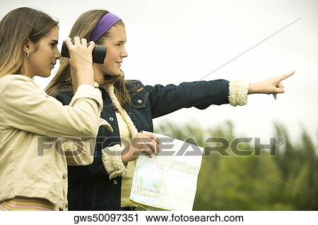 Teenage girl pointing forward with a girl looking through a pair of binoculars View Large Photo Image Stock Image - Teenage girl pointing forward with a girl looking through a pair of binoculars. Fotosearch