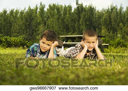 Two boys lying on the lawn View Large Photo Image Stock Photo - Two boys lying on the lawn. Fotosearch