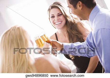 Two young women and a mid adult man toasting View Large Photo Image Stock Image - Two young women and a mid adult man toasting. Fotosearch