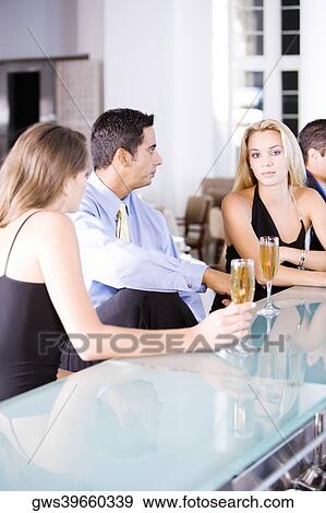 Two young women and a mid adult man sitting at a bar counter View Large Photo Image Stock Photo - Two young women and a mid adult man sitting at a bar counter. Fotosearch