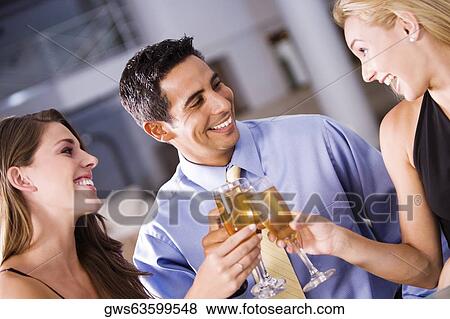 Two young women and a mid adult man toasting View Large Photo Image Stock Photo - Two young women and a mid adult man toasting. Fotosearch