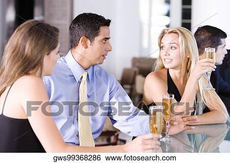Two young women and a mid adult man sitting at a bar counter View Large Photo Image Stock Photograph - Two young women and a mid adult man sitting at a bar counter. Fotosearch
