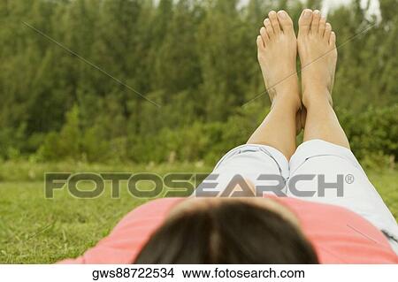 Woman lying on the grass with her feet up View Large Photo Image Picture - Woman lying on the grass with her feet up. Fotosearch