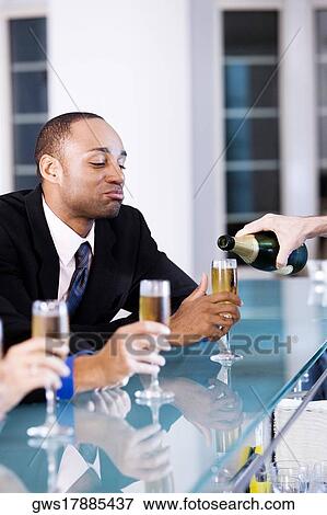 Young man holding a champagne flute at a bar counter View Large Photo Image Stock Photo - Young man holding a champagne flute at a bar counter. Fotosearch