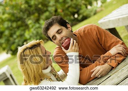 Young woman feeding an apple to a mid adult man View Large Photo Image Stock Image - Young woman feeding an apple to a mid adult man. Fotosearch