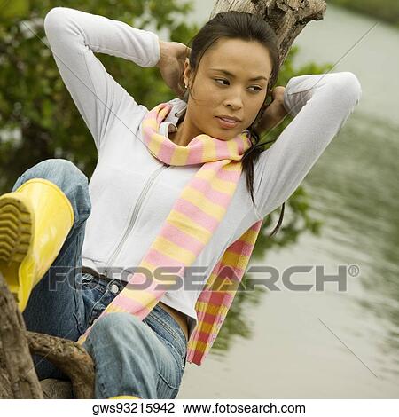 Young woman leaning against a tree stump looking away View Large Photo Image Stock Image - Young woman leaning against a tree stump looking away. Fotosearch